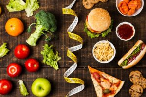 : A comparison image showing a colorful assortment of fresh vegetables on one side and various types of junk food on the other side.